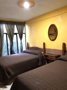 1 dormitorio con 2 camas, espejo y ventana en San Pablo en Pátzcuaro