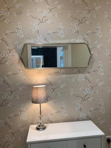 a mirror on a wall with a table and a lamp at Crossing Cottage Sleeps 6 Parking, Family & Contractors Newark in Staythorpe