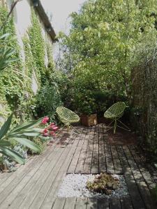 two chairs sitting on a wooden deck in a garden at Le Domaine de Belle in LʼIsle-sur-la-Sorgue