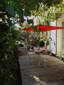 a table and chairs under a red umbrella on a patio at Le Domaine de Belle in LʼIsle-sur-la-Sorgue