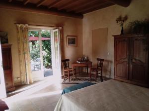 a bedroom with a bed and a table and a door at Le Domaine de Belle in LʼIsle-sur-la-Sorgue
