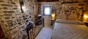 1 dormitorio con cama y pared de piedra en la corte dei cerri, en Spervara