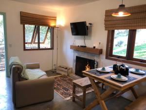 - un salon avec une table et une cheminée dans l'établissement Refúgio Pica-Pau - Monte Verde, à Monte Verde