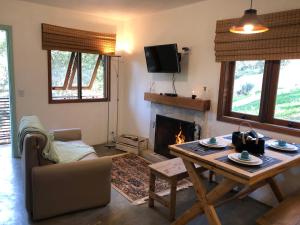 a living room with a table and a fireplace at Refúgio Pica-Pau - Monte Verde in Monte Verde