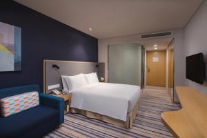 um quarto de hotel com uma cama e uma cadeira azul em Holiday Inn Express Wuxi Taihu New City, an IHG Hotel em Wuxi