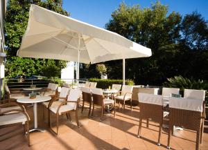 un patio con mesas, sillas y una sombrilla en Hotel Ivka, en Dubrovnik