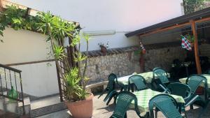 a patio with green chairs and tables and a stone wall at B&B arpaia in Arpaia