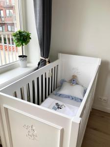 a white crib in a room with a window at Residentie Rapallo Oostende with fantastic Sea View! in Ostend