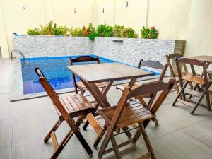 a wooden table and chairs in a room with a pool at Pousada Canoa de Tolda in Piranhas