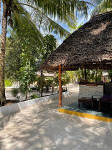 un pabellón con una sombrilla de paja y un banco en Milele Lodge, en Michamvi