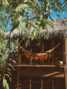 une cabane dans les arbres avec un toit de chaume et un hamac dans l'établissement Pousada Rota dos Ventos, à Barra Grande
