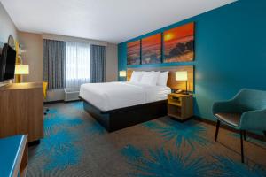 Habitación de hotel con cama y silla en Days Inn by Wyndham Sandusky Cedar Point en Sandusky