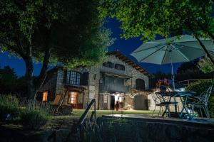 Vallcebre的住宿－Masia Cap del Roc，桌子和雨伞在房子前面
