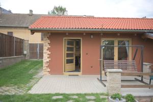 Útulný domek v zahradě v Unhošti nedaleko letiště في Unhošť: منزل صغير أمامه مقعد