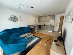 a living room with a blue couch and a kitchen at Apartment MV in Čapljina