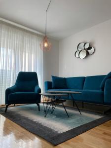 a living room with a blue couch and two chairs at Apartment MV in Čapljina