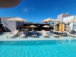 een zwembad met stoelen, tafels en parasols bij Ximena Hotel Boutique in Sayulita