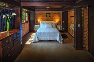um quarto com uma cama e uma parede de tijolos em Sitio na Serra dos Orgaos com rio de aguas cristalinas em Guapimirim