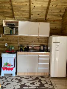 uma cozinha com armários brancos e um frigorífico em Cabana Refúgio canyon Malacara em Praia Grande
