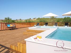 a deck with a pool and a table with drinks at Quinta de São Gabriel in Castro Marim