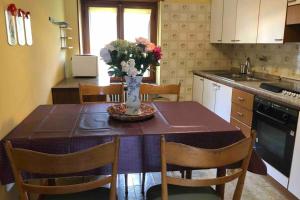 a kitchen with a table with a vase of flowers on it at La Maison des Hirondelles Alloggio ad uso turistico - VDA SAINT-PIERRE 0035 in Saint-Pierre +21 photos