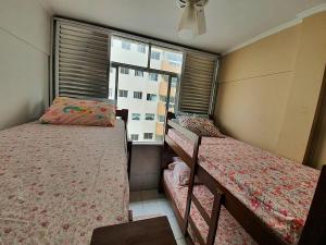 two beds in a small room with a window at Kitnet frente praia Boqueirao in Praia Grande