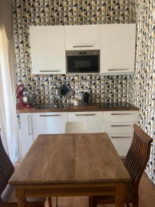 uma cozinha com uma mesa de madeira e armários brancos em Casa del Lago - apartment & rooms em Ispra