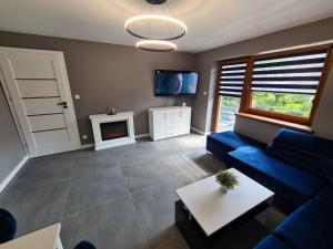 salon z niebieską kanapą i kominkiem w obiekcie Apartamenty River w Wiśle
