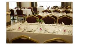 a dining room with tables and chairs with plates and glasses at Hayah Grand Hotel Ex Al Jaad Madinah Hotel in Medina