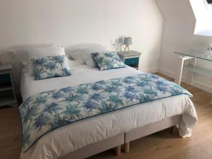 Schlafzimmer mit einem Bett mit blauer und weißer Bettwäsche und Kissen in der Unterkunft Gite 4 places, le Domaine de la Vallée in Saint-Martin-de-Varreville