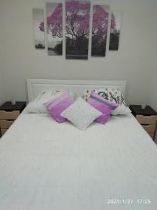 Una cama blanca con almohadas moradas y blancas. en Apartments on Lenina Street 75, en Novosibirsk
