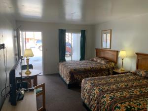 a hotel room with two beds and a television at Economy Inn Kingman in Kingman