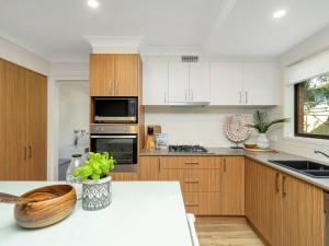 a kitchen with wooden cabinets and a counter top at Catch of the Bay by Experience Jervis Bay in Vincentia