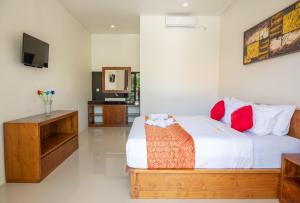 a bedroom with a bed with red pillows and a tv at Mupu Jana G.House Keramas in Keramas