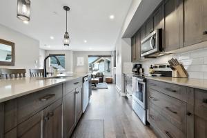 a kitchen with wooden cabinets and a counter top at Spacious Modern Ski-in Ski-out with Hot Tub Townhouse in Sun Peaks