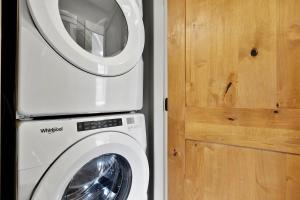 a washing machine sitting next to a wooden door at Spacious Modern Ski-in Ski-out with Hot Tub Townhouse in Sun Peaks