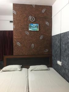 a bedroom with two beds and a brown wall at Kvm Tourist Home in Palakkad