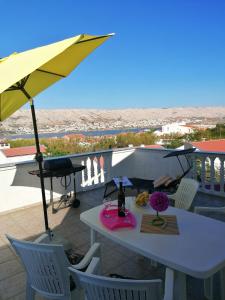 a white table with a yellow umbrella on a patio at Apartments Dario in Pag