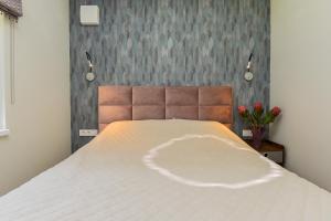 - une chambre avec un lit blanc, une tête de lit et des fleurs dans l'établissement 2Pilkos Lankos Apartaments, à Palanga
