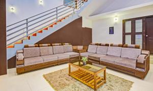 a living room with two couches and a staircase at Treebo Trend Igloo Residency Raja Seat in Madikeri
