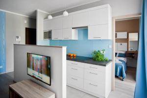 cocina con armarios blancos y TV de pantalla plana en Apartament Luxon 2, en Kielce