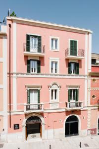 Palazzo della Fontana في ماتيرا: مبنى وردي مع نوافذ خضراء وشرفات