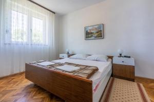 a bedroom with a large bed with white walls at Apartments Rozaria in Dramalj