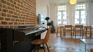 sala de estar con pared de ladrillo y piano en Little Suite - Marianne, en Lille