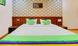 a bedroom with a large white bed with colorful pillows at Treebo Trend Igloo Residency Raja Seat in Madikeri
