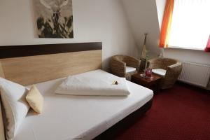 a bedroom with a bed and two chairs and a window at Hotel Cascade Superior in Düsseldorf