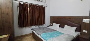 a bedroom with a bed and a window at Hotel Samrat in Dehradun