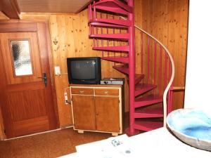 a red spiral staircase in a room with a tv at wooden chalet in Betten near the Aletsch Arena in Betten