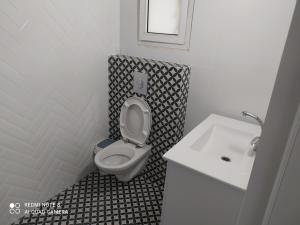 a bathroom with a white toilet and a sink at נופש במושב in Ẕafriyya