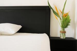 a vase with a plant on a table next to a bed at Double room for a Couple in Puerto Escondido